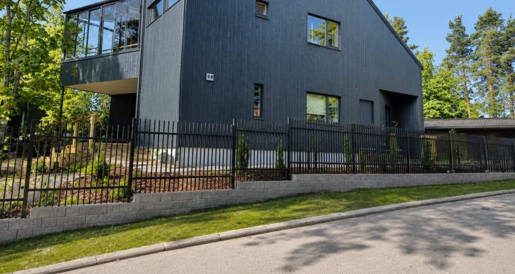 Musta säleaita ja portti asennettuna tukimuuriin